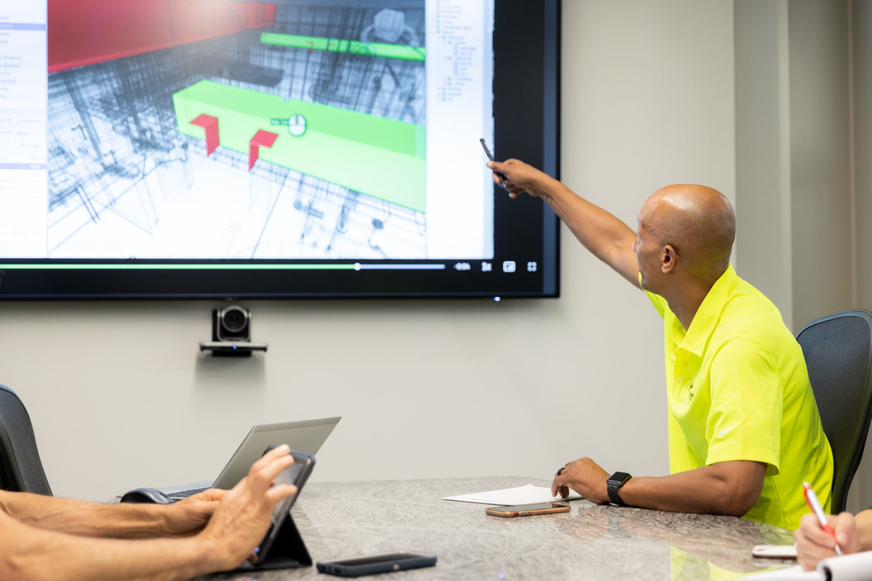 A McCownGordon Construction associate pointing to plans on a screen while in a meeting