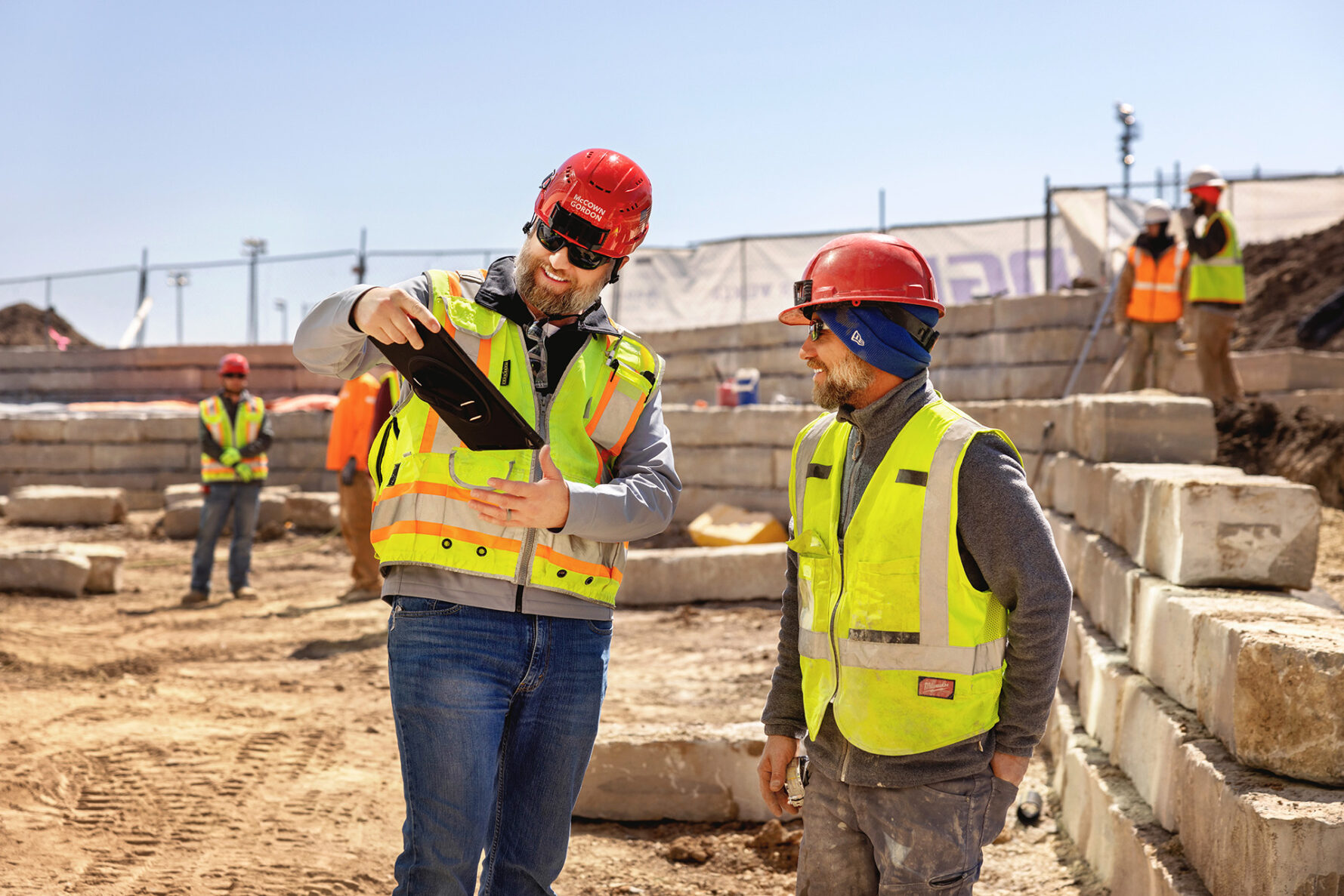 Two McCownGordon Construction associates on a construction site talking and looking at an ipad.