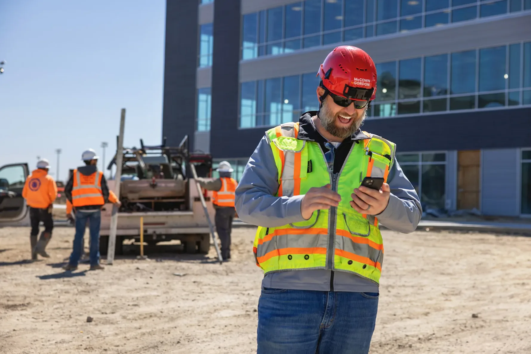 A man laughing and looking at his phone while on a construction job site