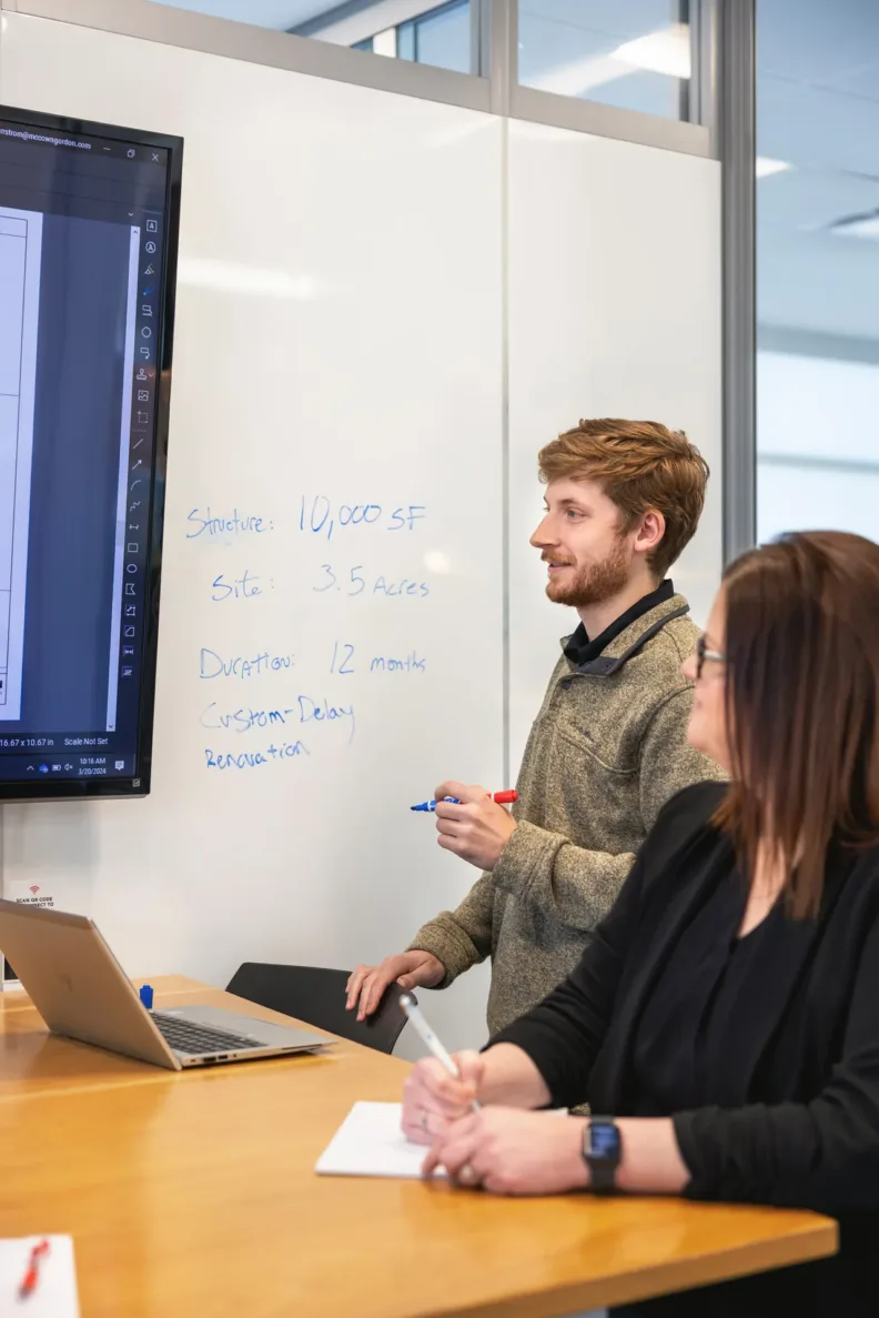 McCownGordon Construction associate writing on a whiteboard during a meeting in Manhattan, Kansas